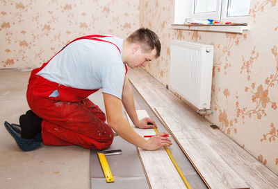 Man measuring hardwood floor panels in home