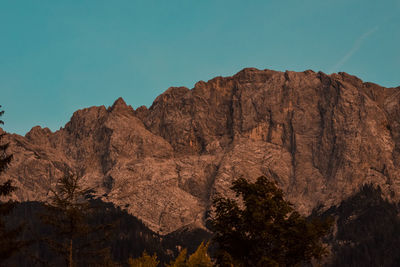 Low angle view of rocky mountains against clear blue sky