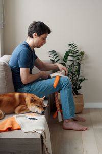 Adult man making diy homemade educational toys for dogs using a tutorial from the internet