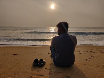 Rear view of man sitting on beach