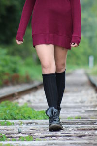 Low section of woman walking amidst railroad track