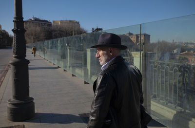 Adult man in hat and leather jacket walking on street. madrid, spain