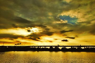 Silhouette bridge over river against sky during sunset