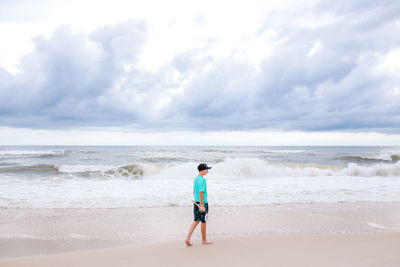 Rear view of man on beach against sky