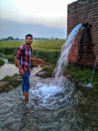 Full length portrait of young man standing in water