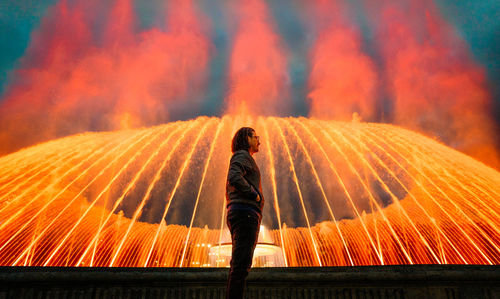 Man in front of illuminated fountain