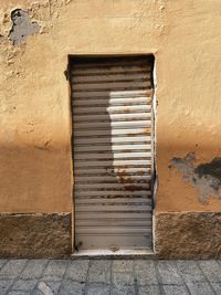 Closed weathered door of house, yellow wall with sunlight and shadows, with copy space and no people 