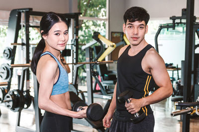 Portrait of young man and woman standing at gym