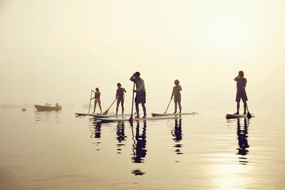A group of standup paddle boarders on a foggy morning at sunrise