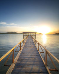 Pier over sea against sky during sunset