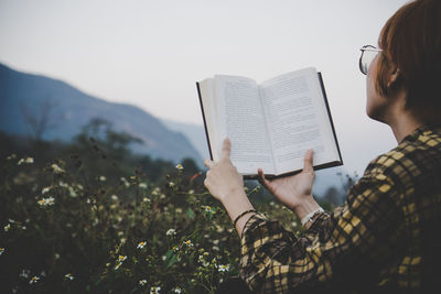 Young woman sitting reading a book at nature in the evening.