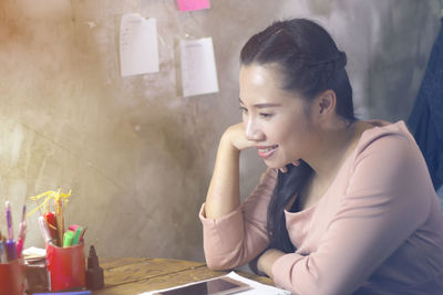 Young woman looking down while sitting on table