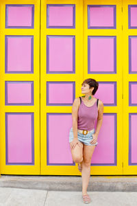 Portrait of young woman standing against wall