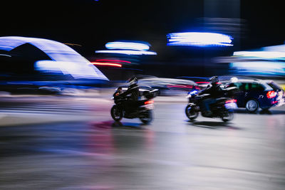 Blurred motion of people riding motorcycle on road at night