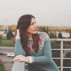 Woman looking away in city against sky