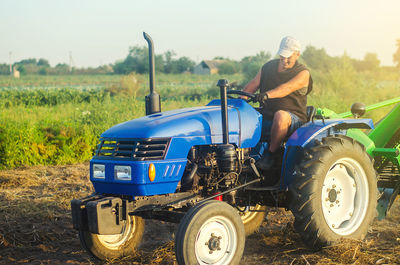 Farmer on a tractor works in the field. digging up the potato crop. farm work. digging vegetables 