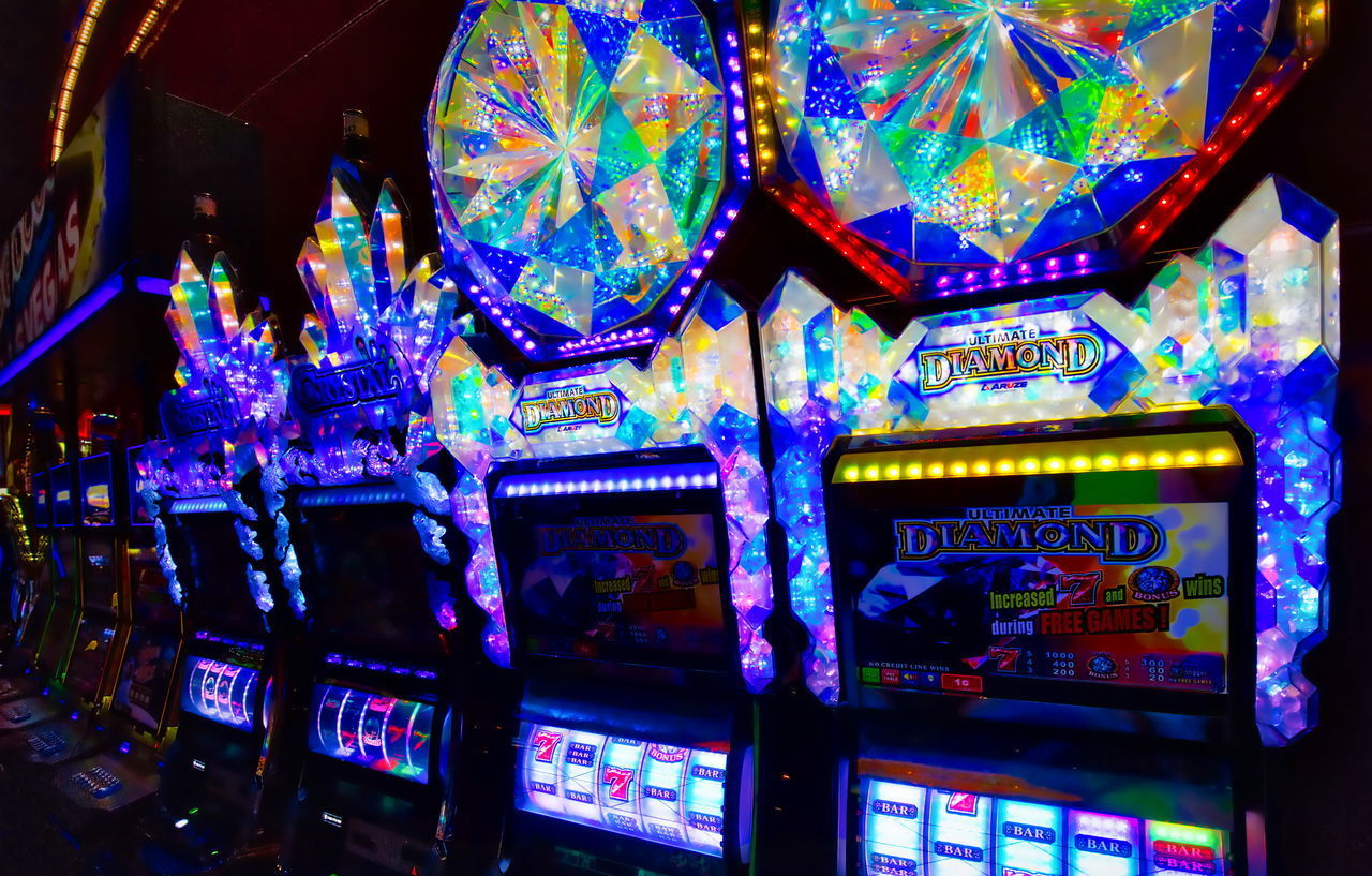 LOW ANGLE VIEW OF ILLUMINATED LIGHTING EQUIPMENT AT AMUSEMENT PARK