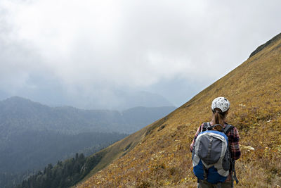 Rear view of young woman hiker with hiking backpack looking at mountain view of the aibga ridge 