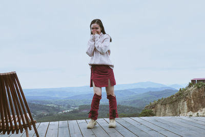 Portrait of young woman standing against mountain