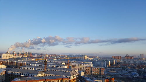 High angle view of buildings in city against blue sky