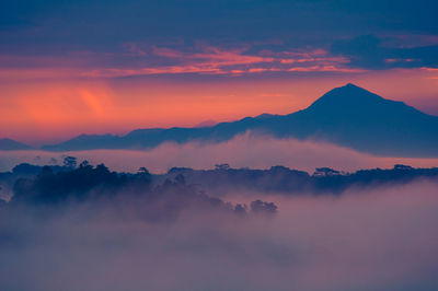 Scenic view of mountains against dramatic sky during sunset