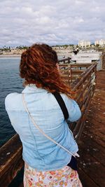 Rear view of woman standing on pier over lake 