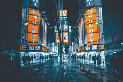 People walking on city street amidst buildings at night