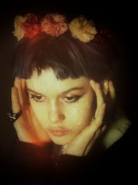 Close-up portrait of young woman against black background