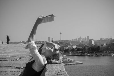 Man photographing with mobile phone against clear sky