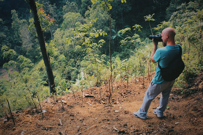 High angle view of mid adult man photographing while standing in forest