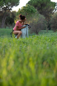 Full length of young woman using mobile phone while standing on field