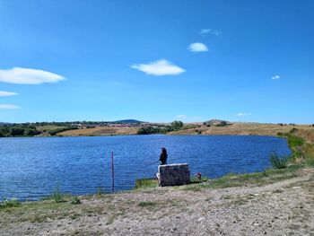 Woman fishing in lake against sky