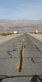 Road leading towards mountain against sky