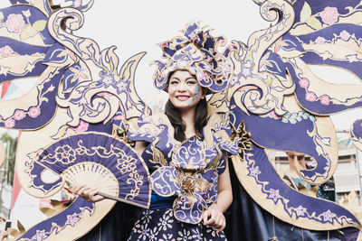 Portrait of smiling young woman standing against wall