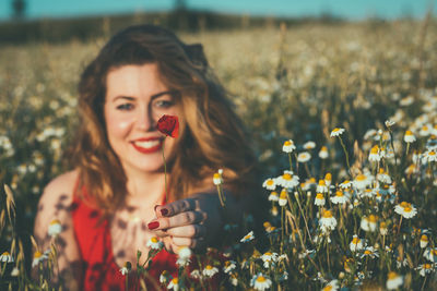 Portrait of woman holding flowers on field