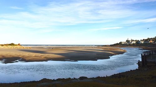 View of calm beach against cloudy sky