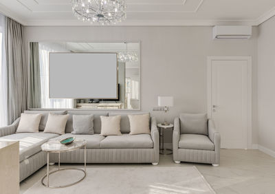 Large grey sofa sofa with armchair in the room with mirrors in gray color in classic style