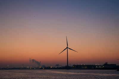 Silhouette of wind turbine against sky during sunset