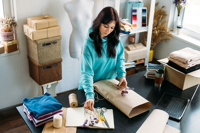 Small business owner woman packs the goods in eco packaging in office, shop.