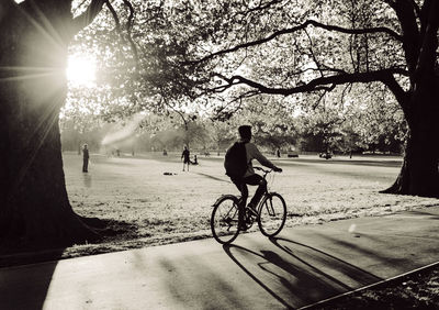 People riding bicycle on road against trees