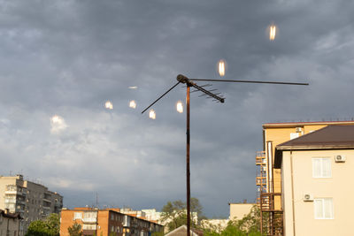 Low angle view of illuminated street light by building against sky