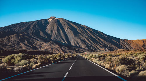 Road by mountain against blue sky at sunset