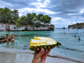 People holding ice cream over sea against sky