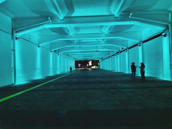 People walking in illuminated tunnel