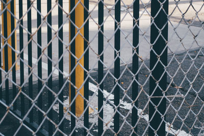 Railing on footpath seen through chainlink fence