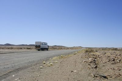 Dirt road on desert against clear blue sky