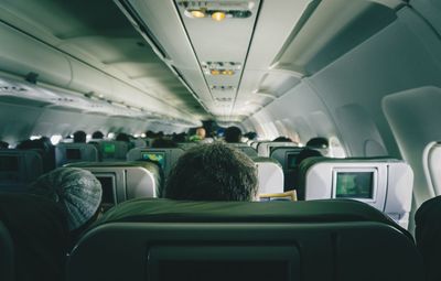 Rear view of passengers sitting on vehicle seats in airplane