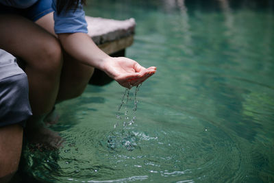 Midsection of woman splashing water by lake