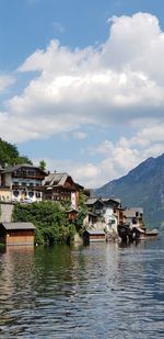 Houses by lake and buildings against sky