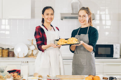 Happy friends standing on cutting board at home